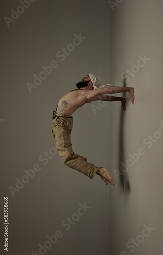 Flying bridge. Male sportsman training shirtless, doing flexible yoga exercises over studio background. Muscular body shape. Art of movement, male body aesthetics, health, sportive lifestyle concept