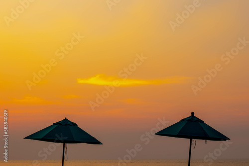 Sun protection from concept, Silhouette of classic vintage pool umbrella with golden sunlight in the evening, Fabric umbrella pole on the seaside sunset as background, Relaxation and rest under shade.