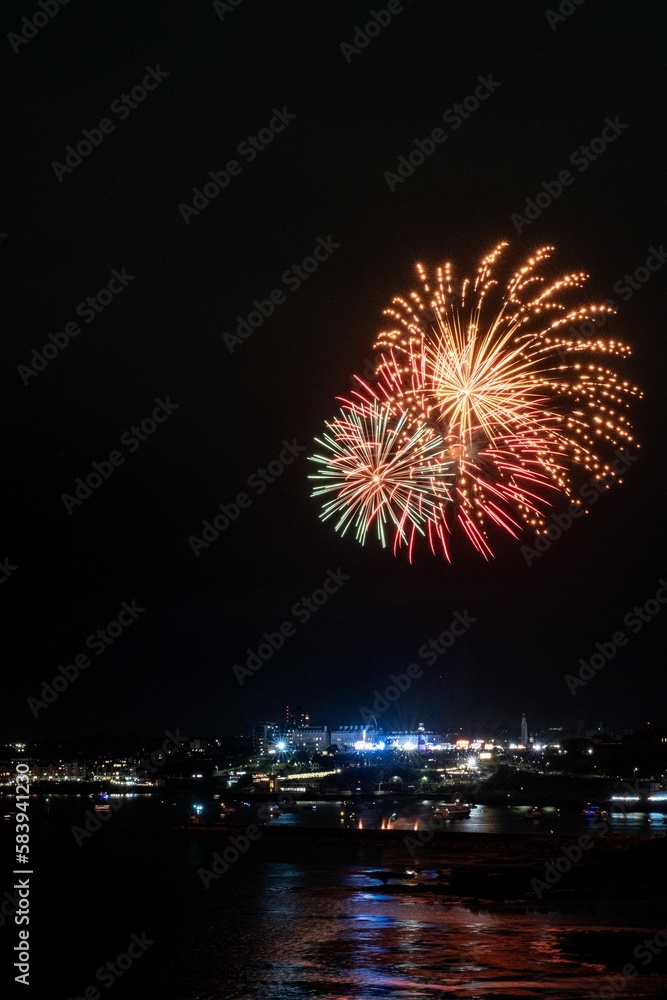 Fireworks during British firework championships exploding over illuminated city Plymouth Cornwall