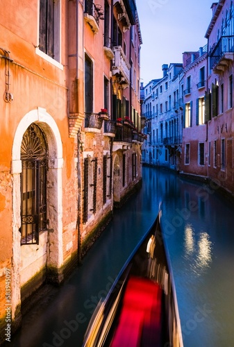 Gondola boat floating through a narrow waterway at night