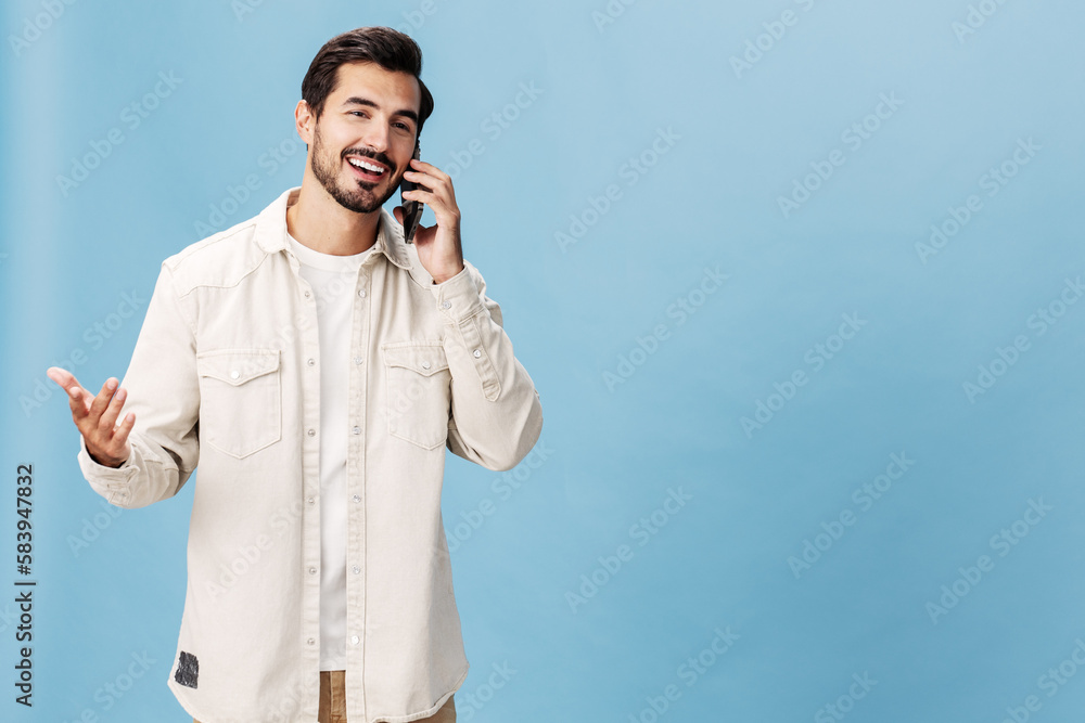 Portrait of a man brunette animation and joy talking on the phone smile with teeth, on a blue background in a white T-shirt and jeans, copy space Portrait of a man brunette animation and joy talking on the phone smile with teeth, on a blue background in a white T-shirt and jeans, copy space