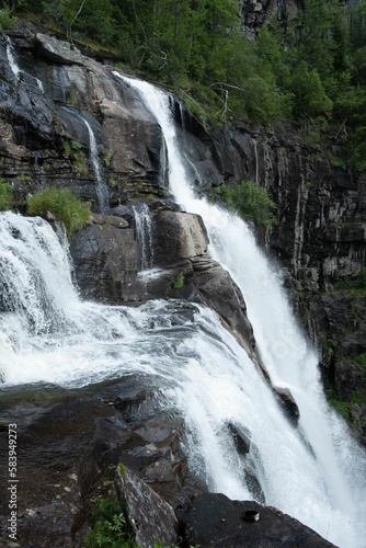 Fototapeta Naklejka Na Ścianę i Meble -  Vertical shot of the flowing Steindalsfossen waterfall in the mountains of Norway