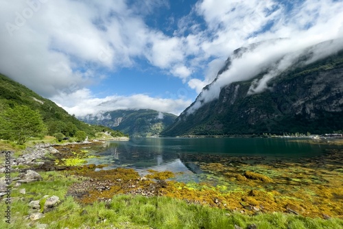 Drone shot of the lake surrounded by cloud-covered green hills at Geiranger Fjord, Norway