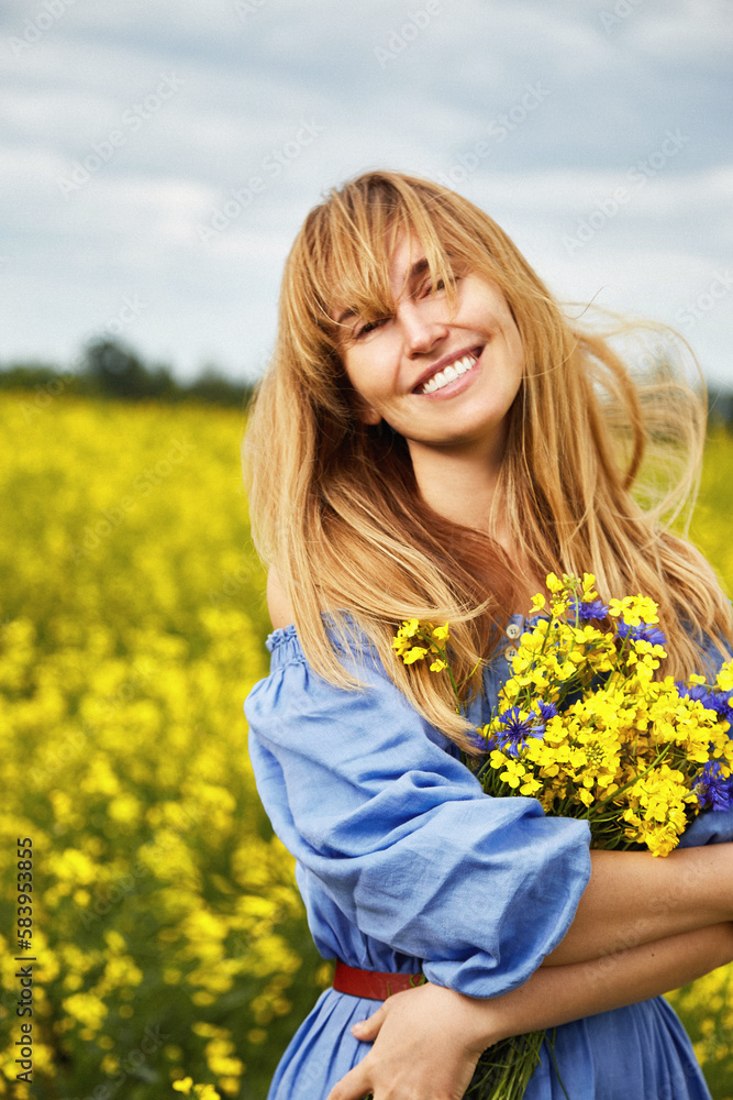 Beautiful blond woman walk on the summer spring park yellow and blue flowers landscape warm weather smile and happy freedom physical and mental health and well-being herbal natural lifestyle eco. Beautiful blond woman walk on the summer spring park yellow and blue flowers landscape warm weather smile and happy freedom physical and mental health and well-being herbal natural lifestyle eco.
