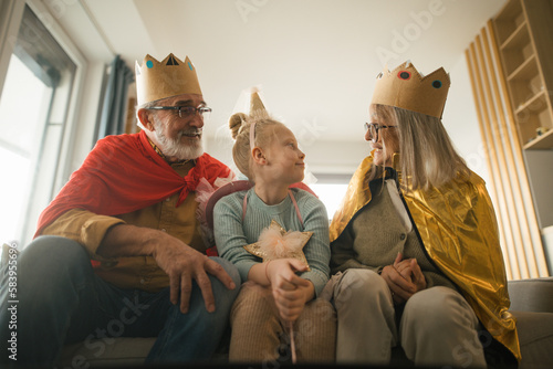 Grandparents playing with their little granddaughter, having costumes. photo