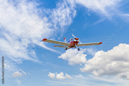 Single engine ultralight plane flying in the blue sky with white clouds	