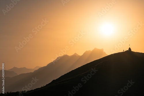 Silhouette of a man by a flag in the Swiss Alps at sunset