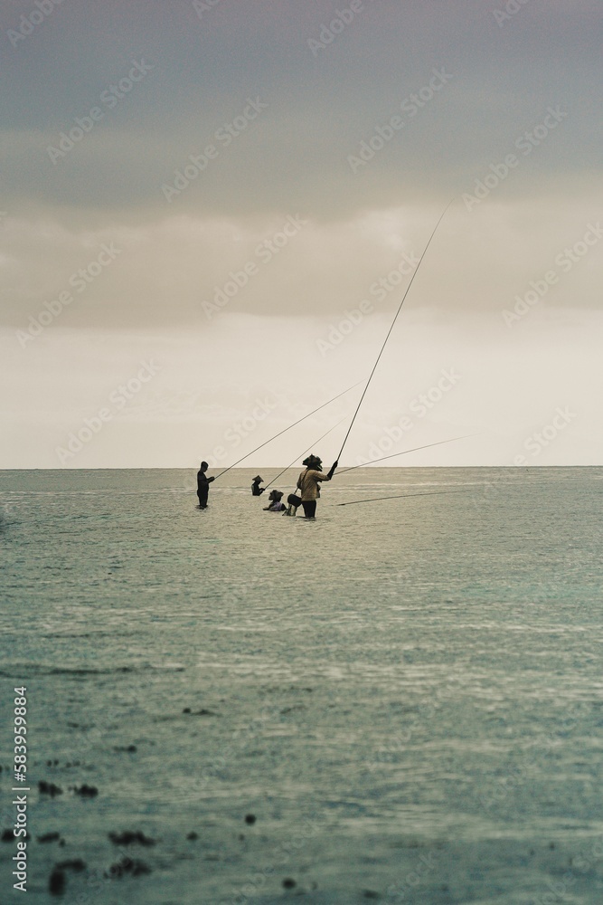 Men throwing fishing rods into the sea