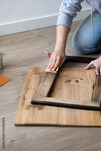 woman's hands doing DIY work in her living room.young woman sanding a wooden piece of furniture