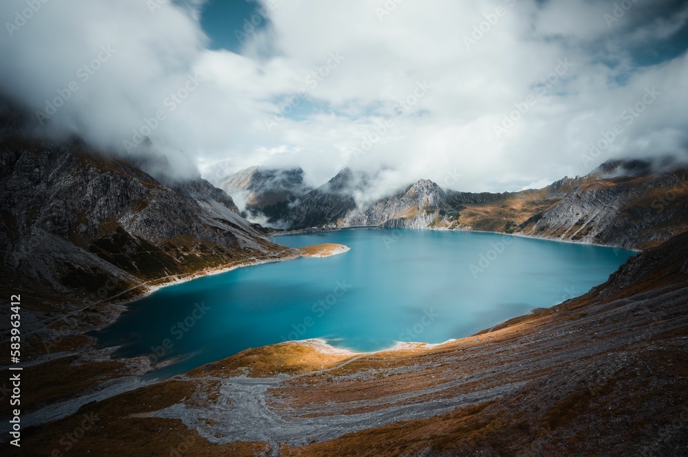 Beautiful view of a blue lake surrounded by mountains under the cloudy sky