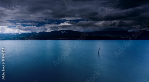 Scenic shot of the calm waters of a lake underneath a cloudy sky