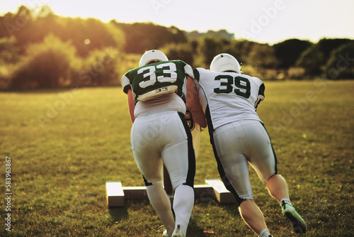 Football players practicing with a tackle sled photo