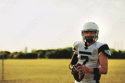 Football quarterback standing with a ball on a field