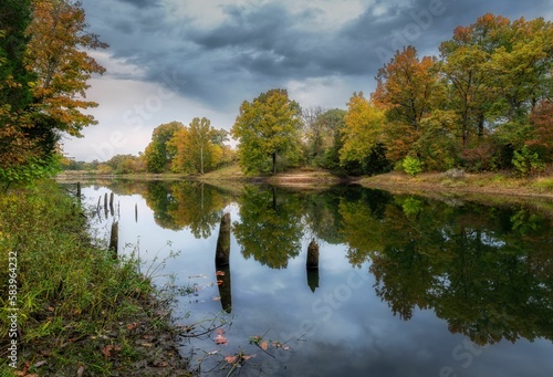 Long exposure shot of trees reflecting in a lake in autumn. © Michael K Greer/Wirestock Creators