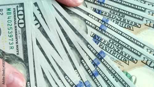 Money is in the hands of a person. Recalculation of money. Money in 100 dollar bills. A person counts money.