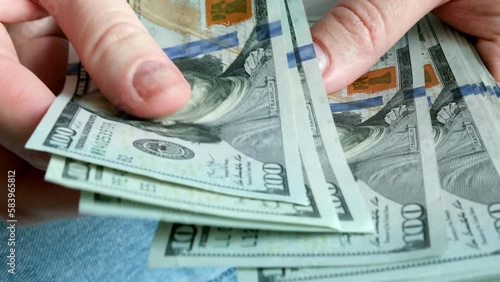 Money is in the hands of a person. Recalculation of money. Money in 100 dollar bills. A person counts money.