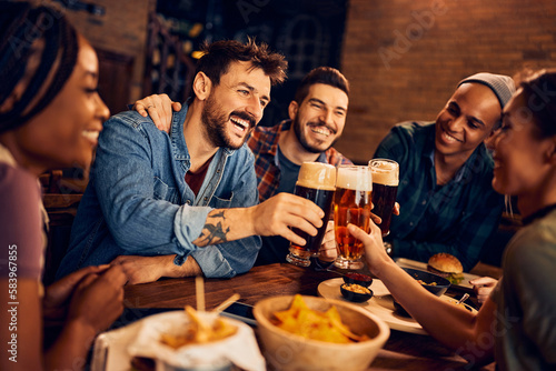 Fototapet Cheerful man and his friends toast with beer while gathering in bar