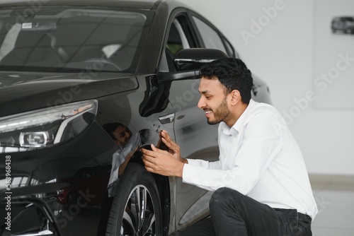 A young Indian man chooses a new car at a car dealership © Serhii