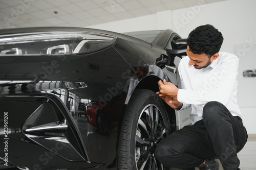 happy indian man buy new biodiesel eco automobile in lux showroom.