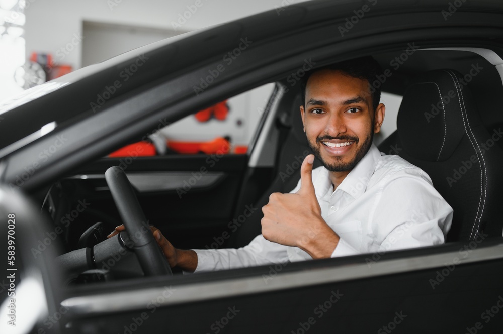 A young Indian man chooses a new car at a car dealership
