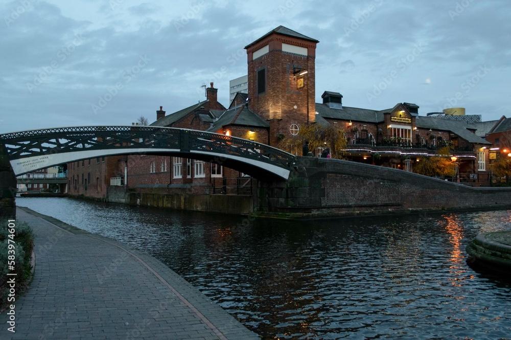 Scenic view of old buildings and a bridge on a canal in Birmingham, England at dusk