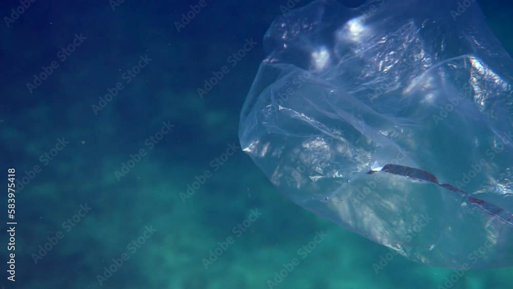 A discarded plastic bag floats in the water, dangers of ocean pollution