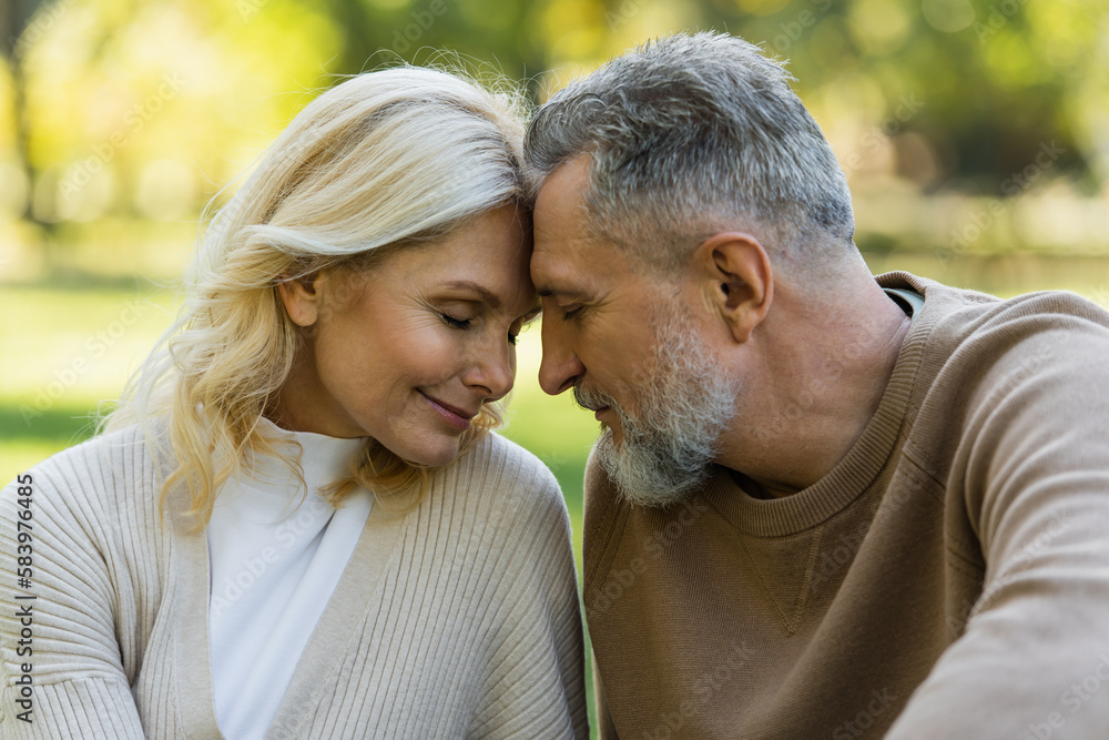 Obraz premium happy middle aged couple sitting face to face with closed eyes during springtime.