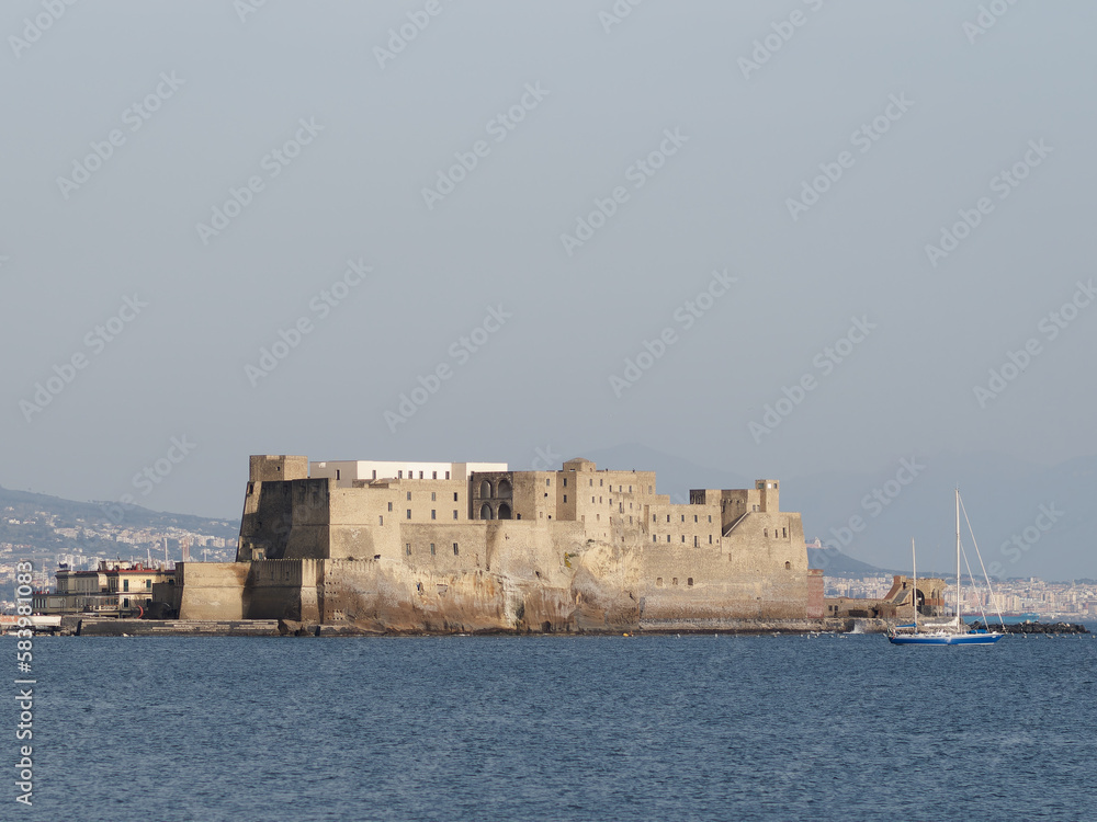 Naples, Italy. Castel dell'Ovo with breakwater rocks in the foreground and with a beautiful sunset sky.