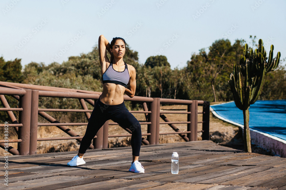 Latin young woman stretching exercises outdoor at park in Mexico, hispanic female fitness sport