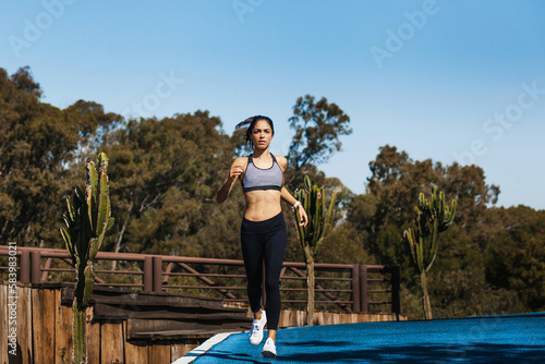 Latin young woman running outdoors in park at Mexico, Hispanic female fitness sport © Marcos