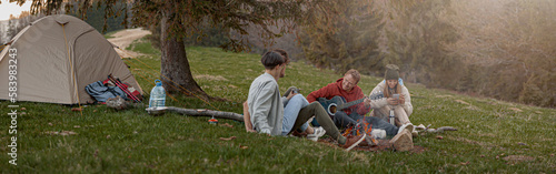Caucasian team of friends hikers resting with guitar playing at tent in mountains. . © Kostiantyn