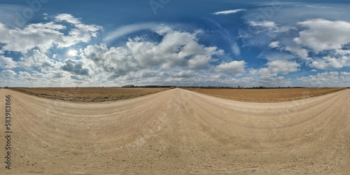 spherical 360 hdri panorama on gravel road with clouds and sun on blue sky in equirectangular seamless projection  use as sky replacement in drone panoramas  game development as sky dome or VR content