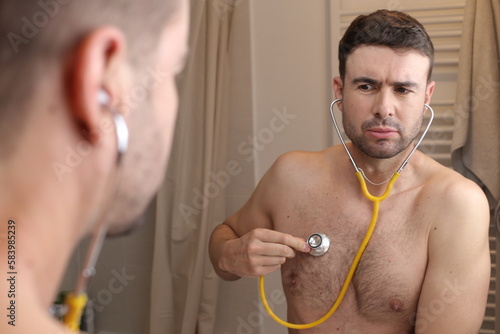 Hypochondriac man listening to his own heartbeat   photo