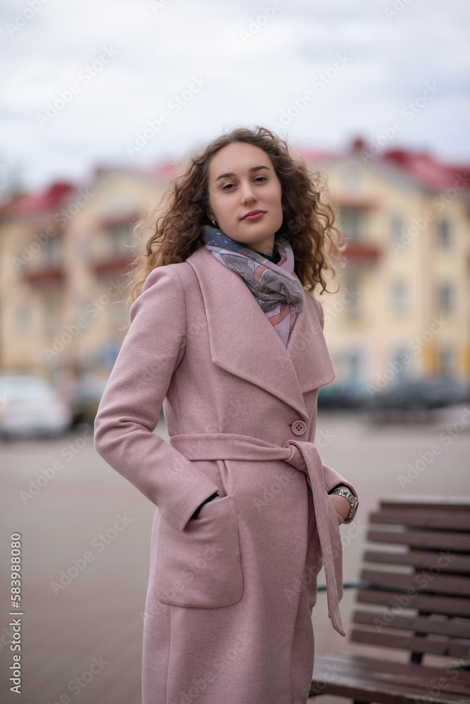 Portrait of a young beautiful blonde long-haired girl in a gray coat in spring. Portrait of a young beautiful blonde long-haired girl in a gray coat in spring.