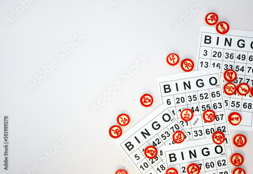Many wooden chips with numbers and cards for a board game of bingo or lotto on a light background.