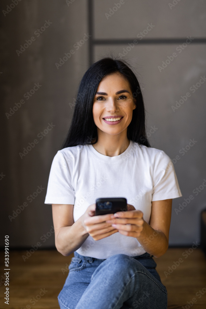 Young woman sits on wooden stairs. Pretty tanned lady in linen pants and jacket holds phone. Young woman sits on wooden stairs. Pretty tanned lady in linen pants and jacket holds phone.