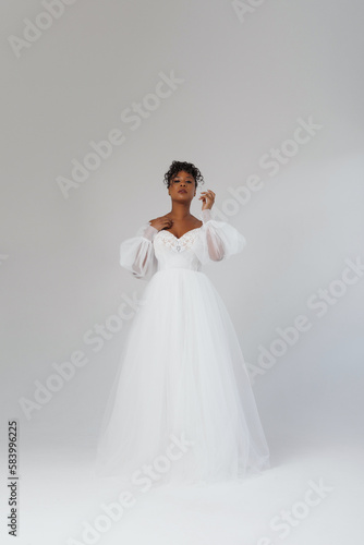 Beautiful African American woman posing in a wedding dress. Fashion model in a white dress.