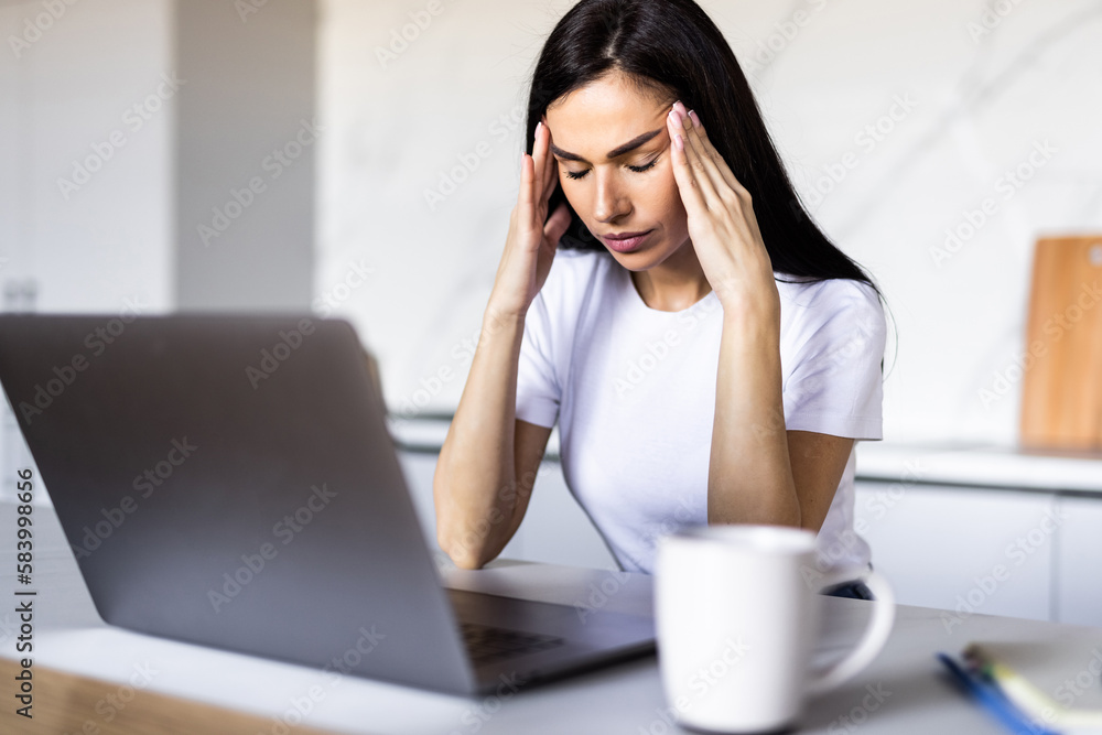 Concerned young woman thinking over domestic paperwork, sitting at laptop computer, papers, calculator at home, touching face, head, analyzing bills, taxes, expenses, financial problems Concerned young woman thinking over domestic paperwork, sitting at laptop computer, papers, calculator at home, touching face, head, analyzing bills, taxes, expenses, financial problems