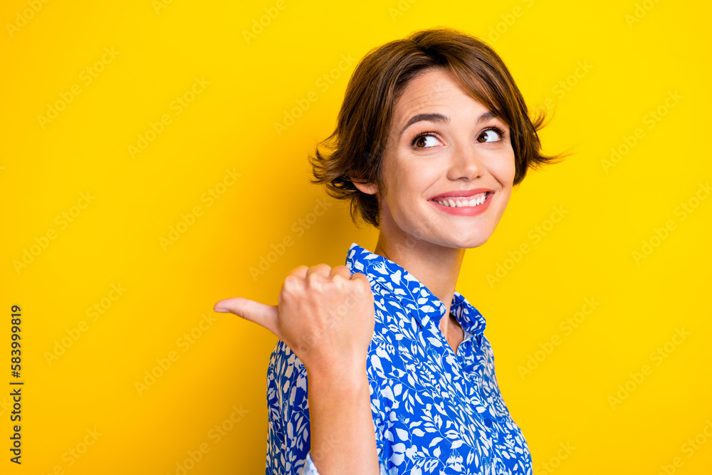 Photo of pretty dreamy woman dressed blue blouse looking pointing thumb back empty space isolated yellow color background Photo of pretty dreamy woman dressed blue blouse looking pointing thumb back empty space isolated yellow color background