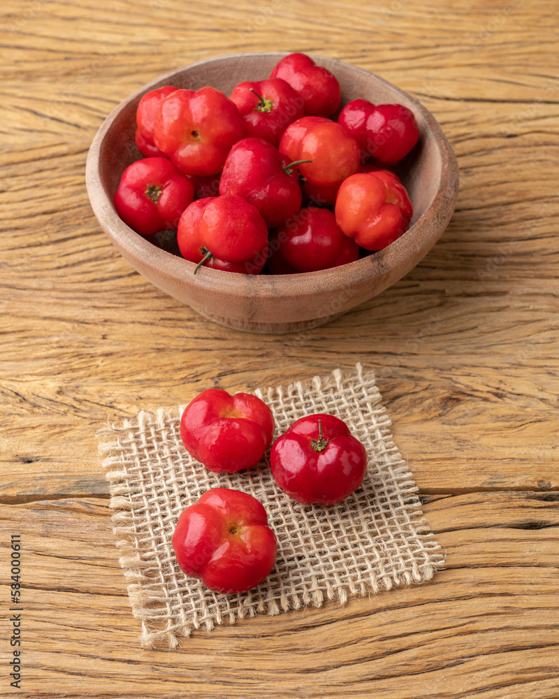 Acerolas or Barbados Cherries in a bowl over wooden table Acerolas or Barbados Cherries in a bowl over wooden table