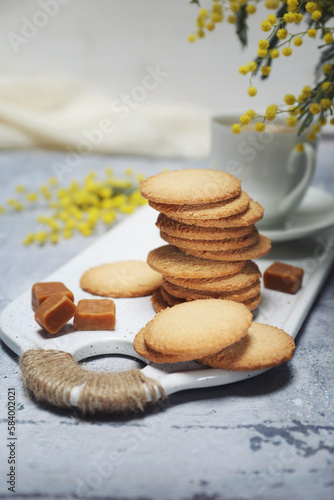 Palets bretons, french cookies. Salted caramel Shortbread Breton cookies, cup of coffee and bouquet of mimosa