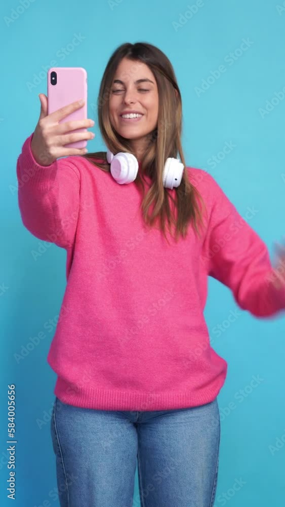 Smiling woman in headphones using smartphone having a videcall. Vertical video. Smiling woman in headphones using smartphone having a videcall. Vertical video.