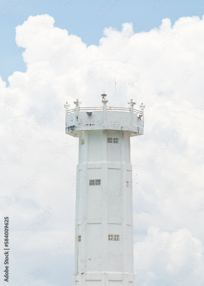 white lighthouse in front of a cloudy bright sky 