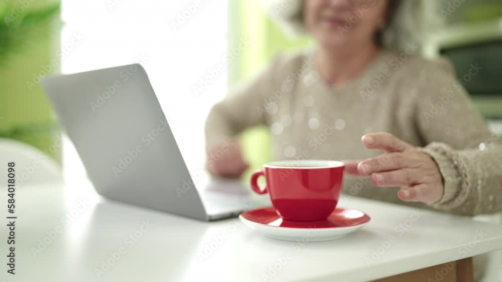 Middle age woman with grey hair holding cup of coffee standing at home Middle age woman with grey hair holding cup of coffee standing at home