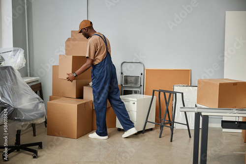African American loader in uniform carrying boxes in new office