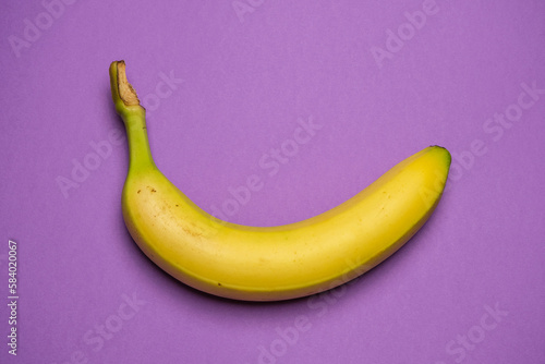 Ripe banana isolated on purple background. Creative Thinking concept, minimalism. 