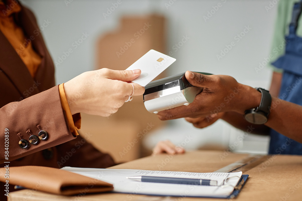Close-up of young woman paying for moving service with credit card - obrazy, fototapety, plakaty 