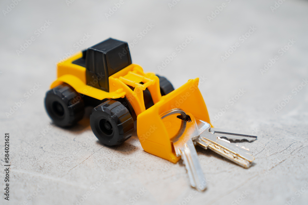 Obraz premium Little toy buldozer pushing big keys and key chain