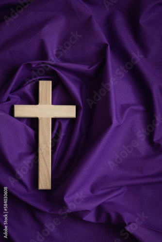 Wood cross on a purple fabric background with copy space