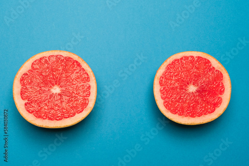 Juicy organic grapefruit cut in half on a blue background. Cool minimal flat lay, copy space. Healty breakfast or diet concept. (ID: 584030872)